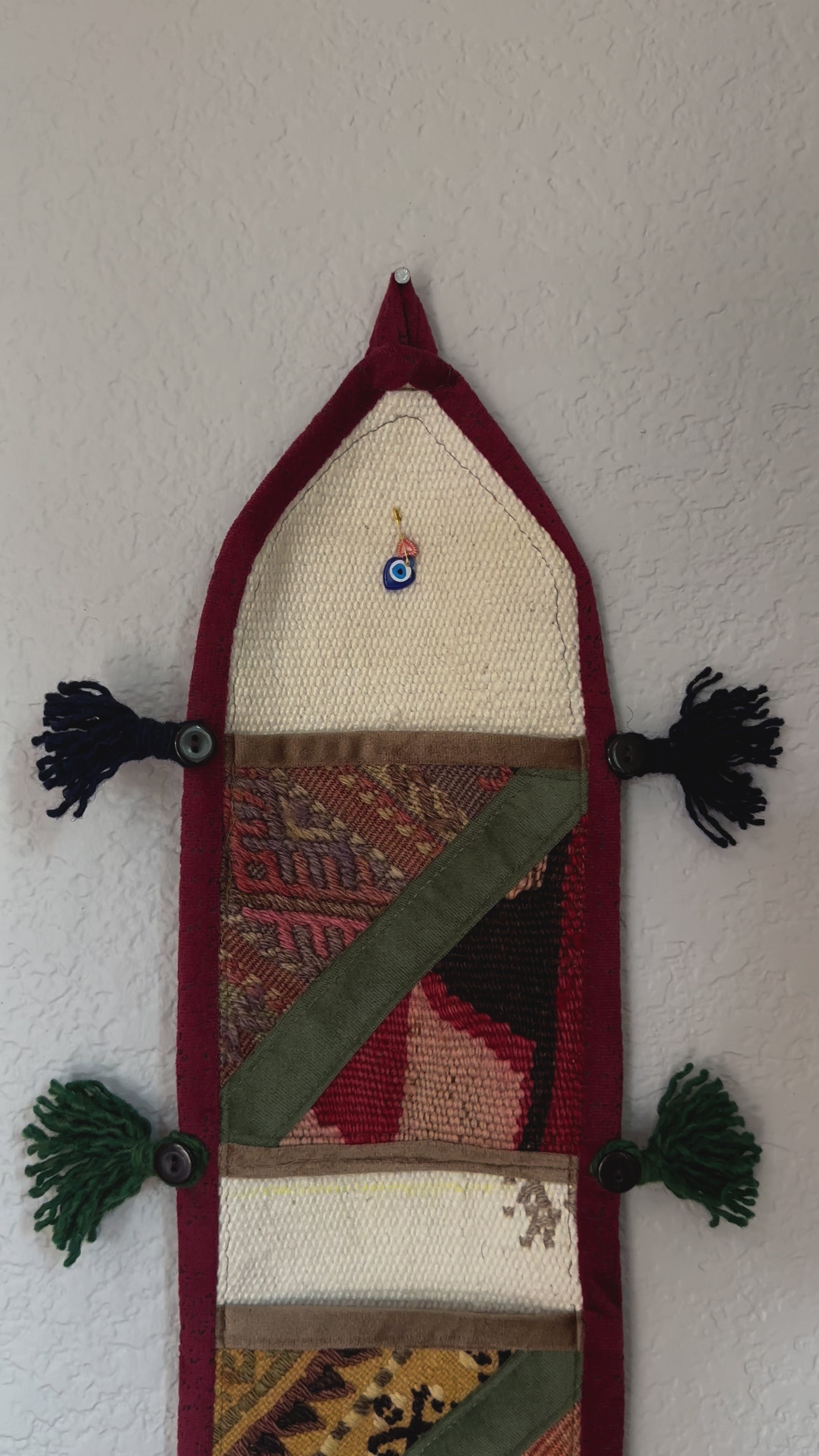 multi-colored three pocket wall organizer made from scraps of colorful Turkish kilim rugs with yarn tassels at each end