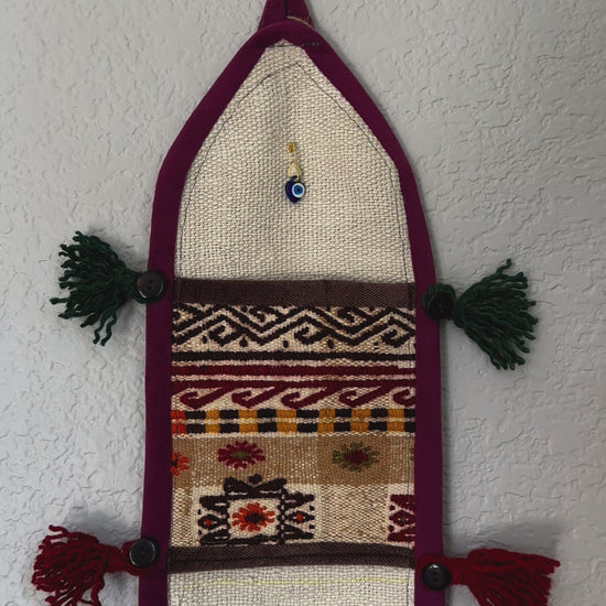 multi-colored three pocket wall organizer made from scraps of colorful Turkish kilim rugs with yarn tassels at each end