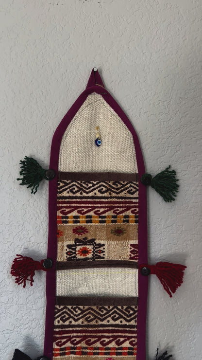 multi-colored three pocket wall organizer made from scraps of colorful Turkish kilim rugs with yarn tassels at each end