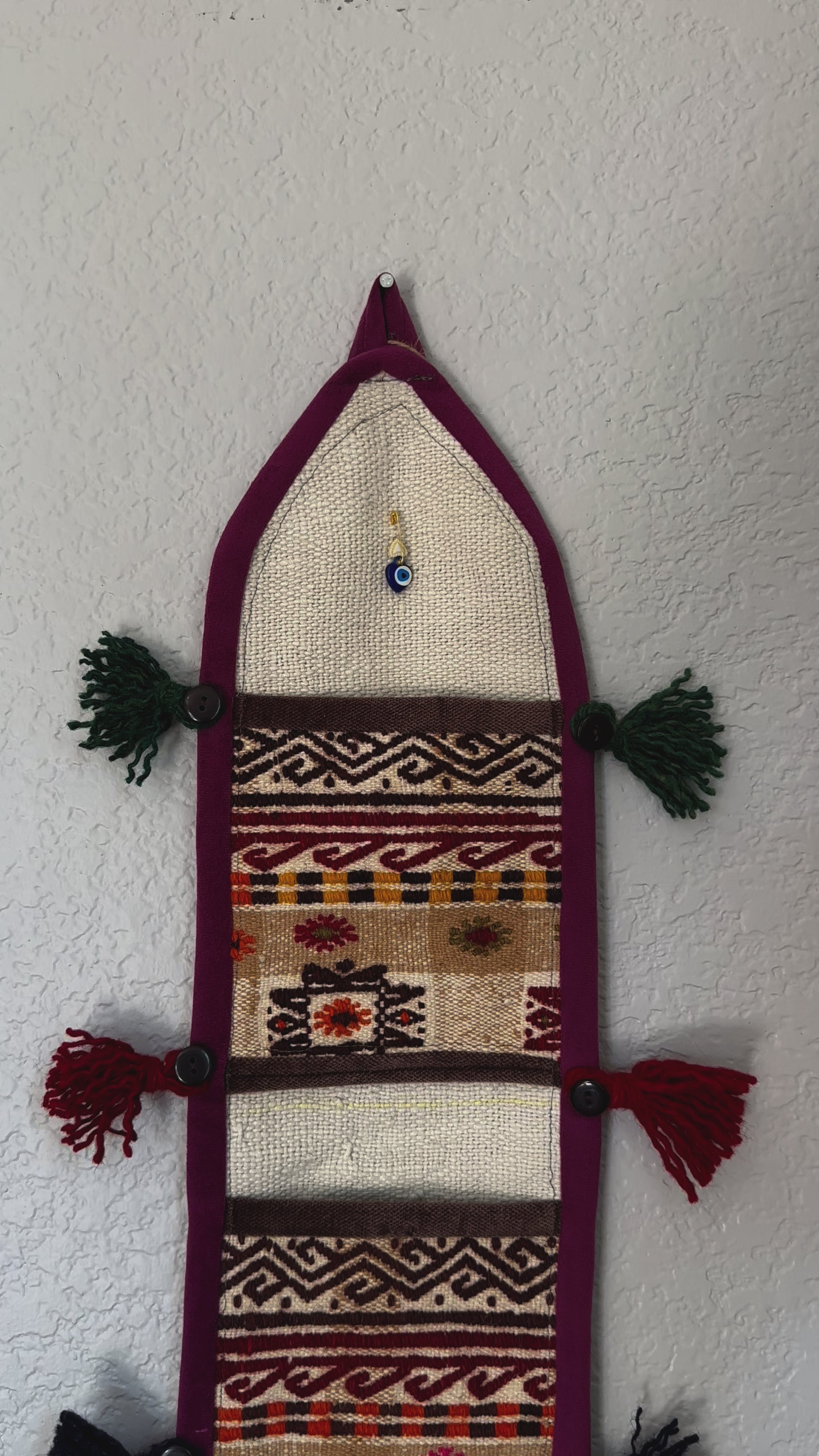 multi-colored three pocket wall organizer made from scraps of colorful Turkish kilim rugs with yarn tassels at each end