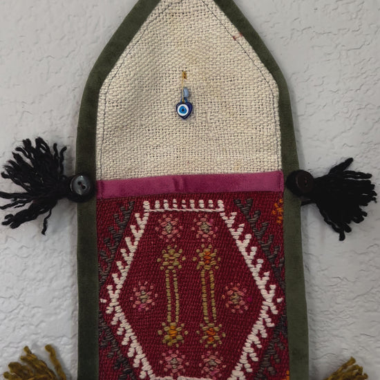 multi-colored three pocket wall organizer made from scraps of colorful Turkish kilim rugs with yarn tassels at each end