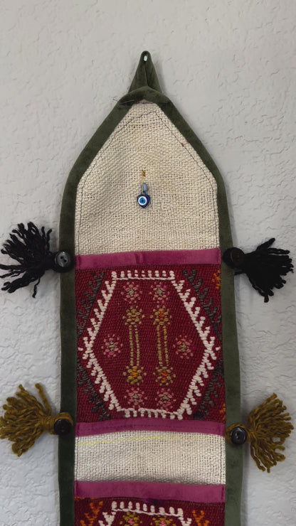 multi-colored three pocket wall organizer made from scraps of colorful Turkish kilim rugs with yarn tassels at each end