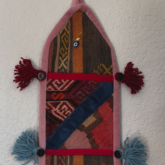 multi-colored three pocket wall organizer made from scraps of colorful Turkish kilim rugs with yarn tassels at each end