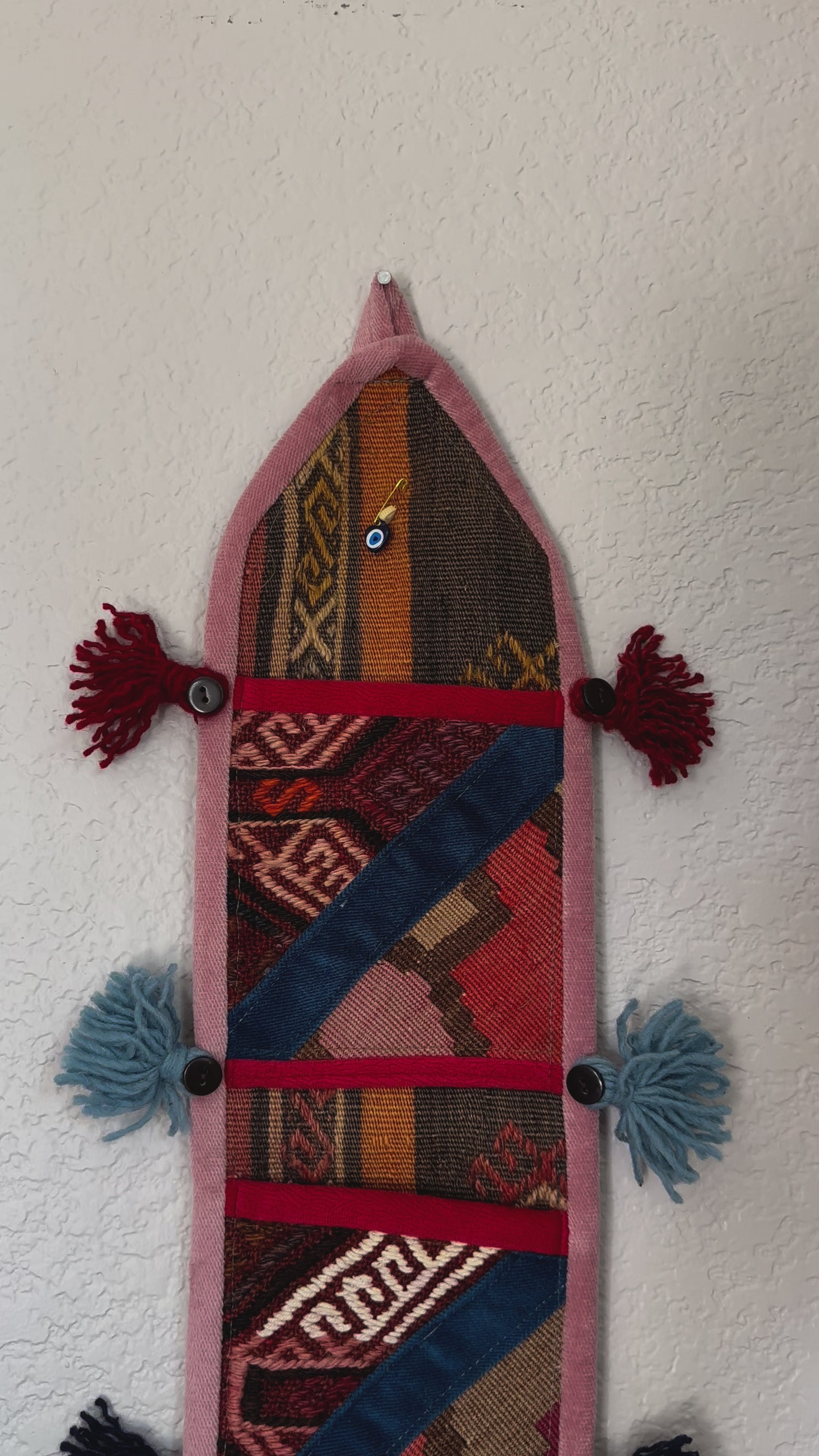 multi-colored three pocket wall organizer made from scraps of colorful Turkish kilim rugs with yarn tassels at each end