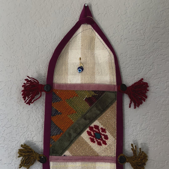 multi-colored three pocket wall organizer made from scraps of colorful Turkish kilim rugs with yarn tassels at each end