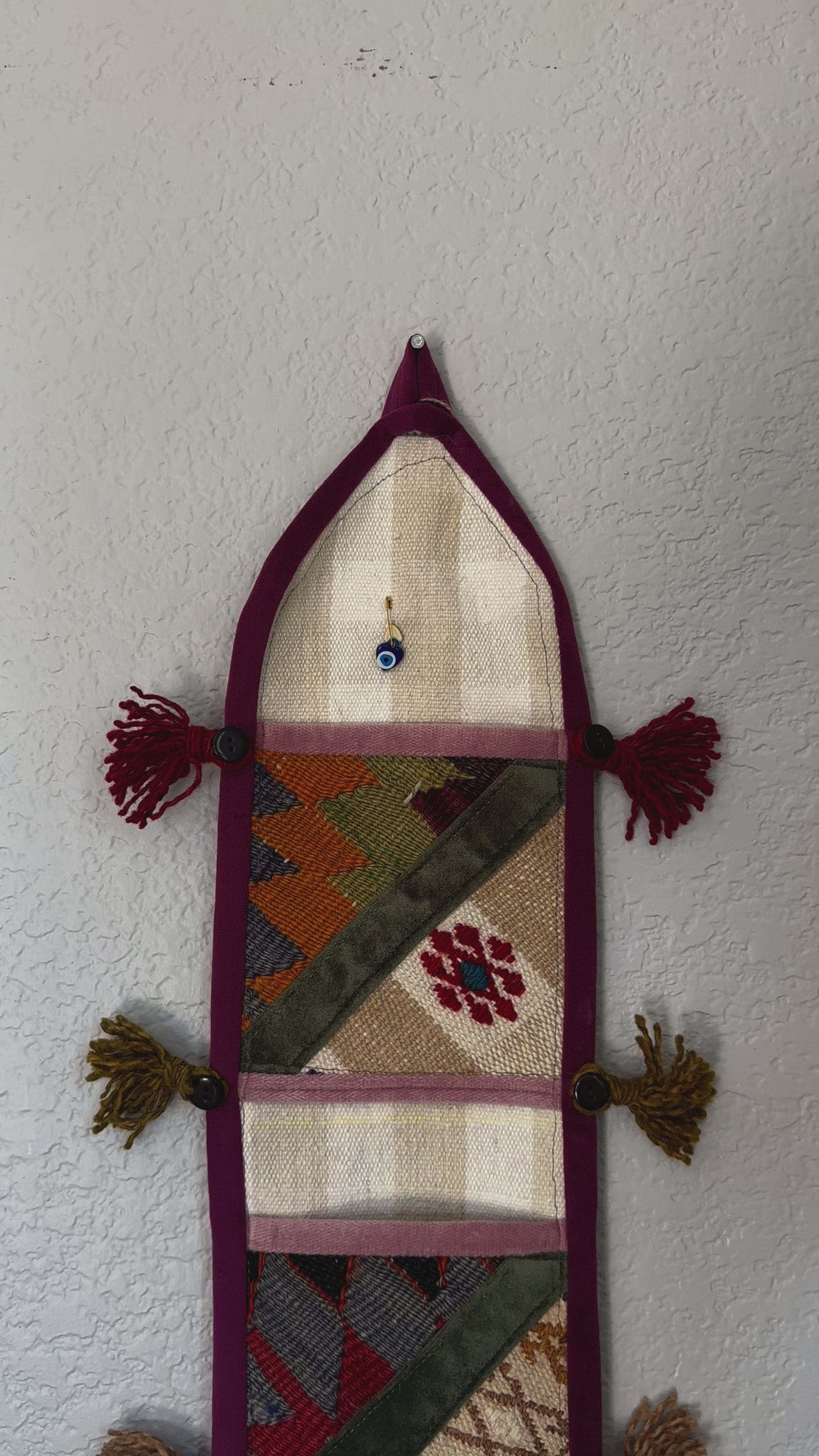 multi-colored three pocket wall organizer made from scraps of colorful Turkish kilim rugs with yarn tassels at each end