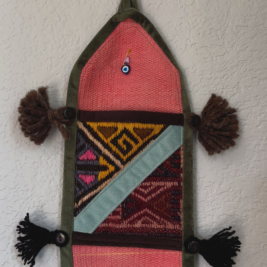 multi-colored three pocket wall organizer made from scraps of colorful Turkish kilim rugs with yarn tassels at each end