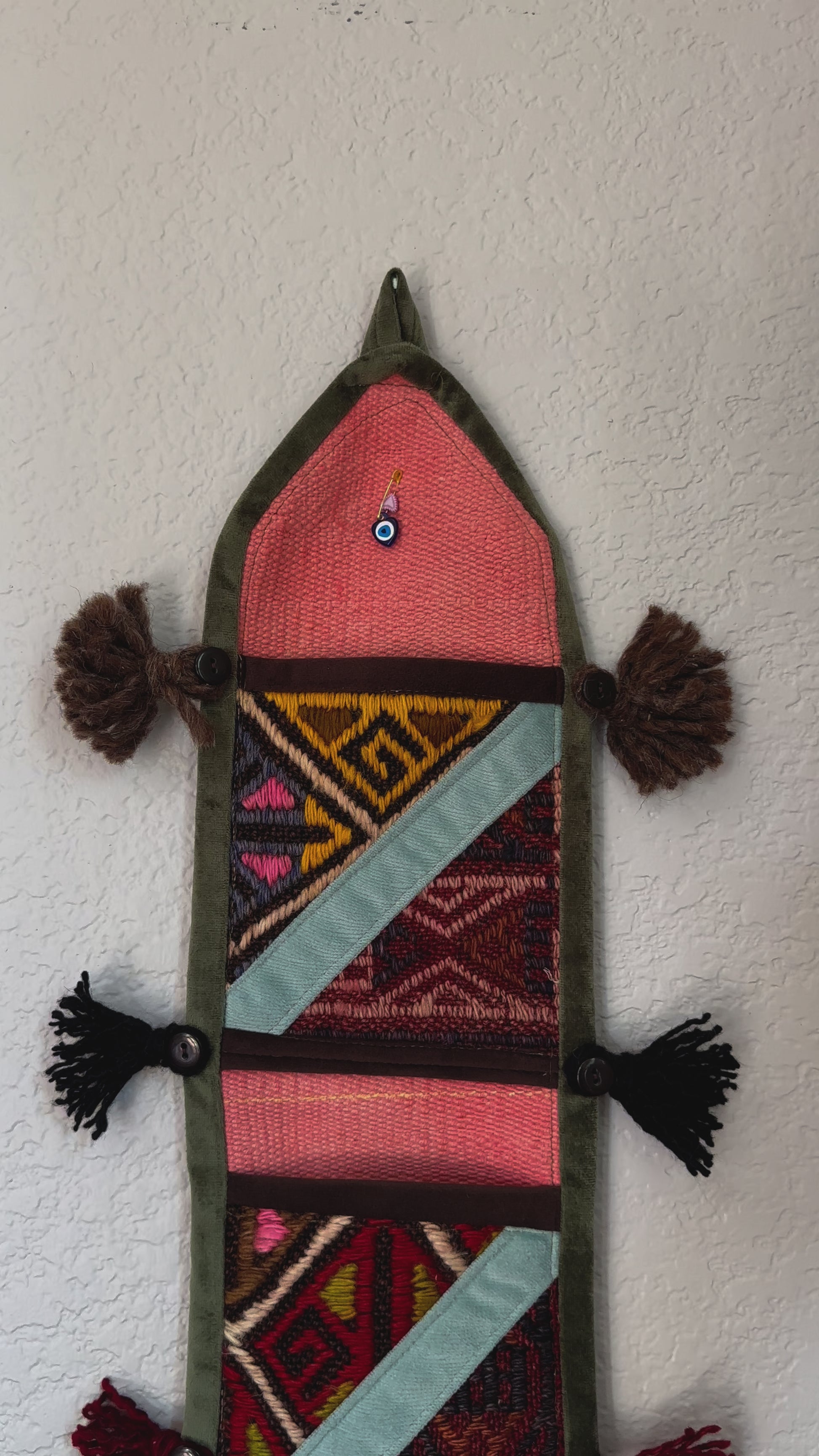 multi-colored three pocket wall organizer made from scraps of colorful Turkish kilim rugs with yarn tassels at each end